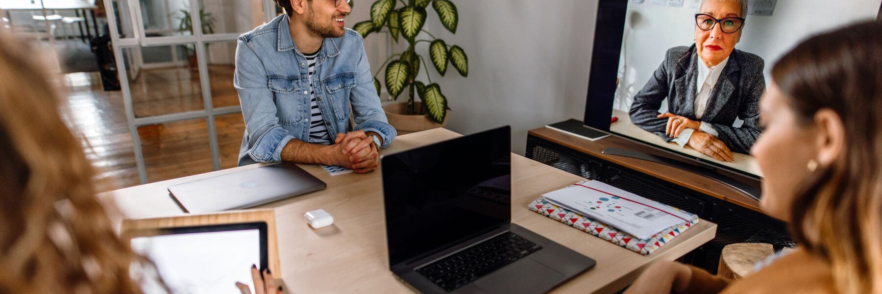 in office workers on computers, remote worker on large screen