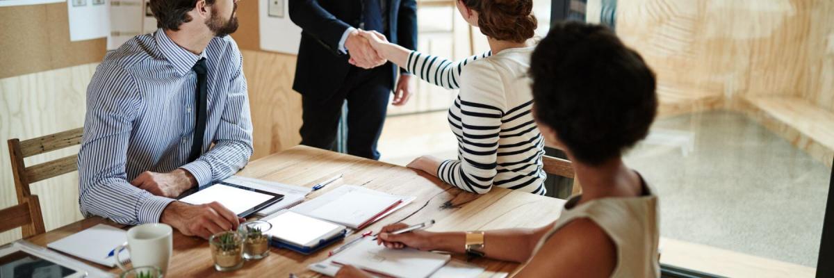 Business people greeting man in suit at a table of papers