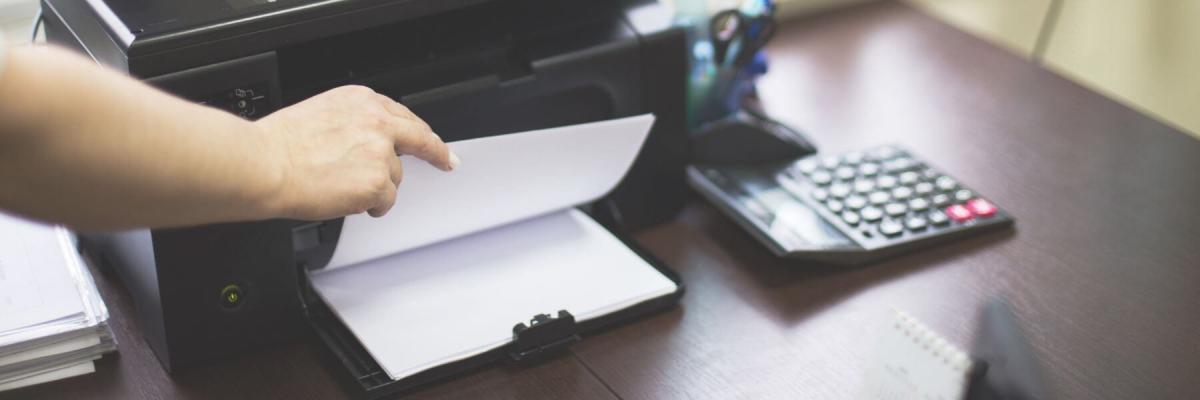 hand flipping through printer paper in print tray