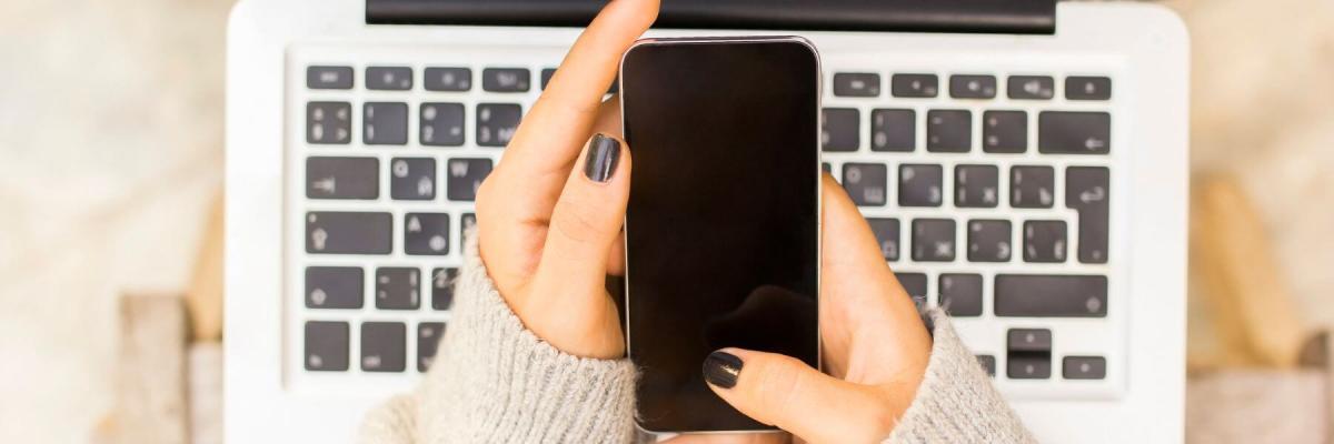 holding a cell phone over a laptop keyboard