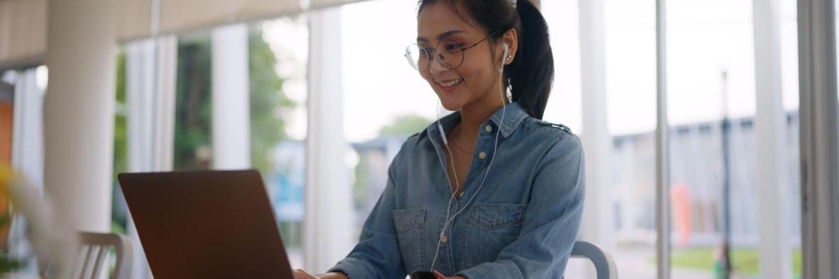 woman working on laptop with earbuds in