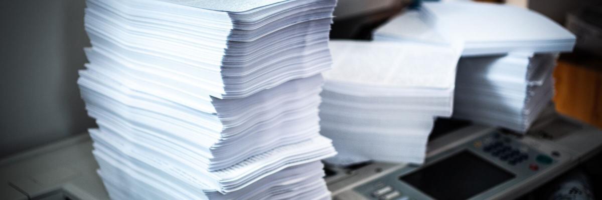 piles of printer paper atop printers