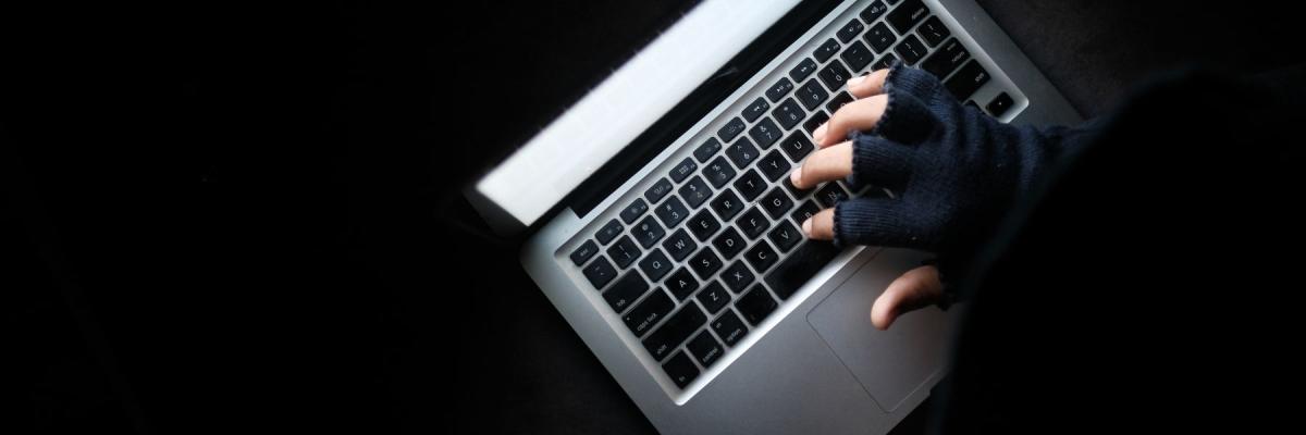 dark figure with gloves on laptop